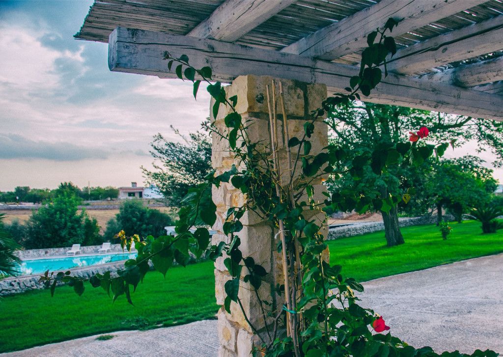 A stone pillar with climbing plants and a wooden pergola structure.