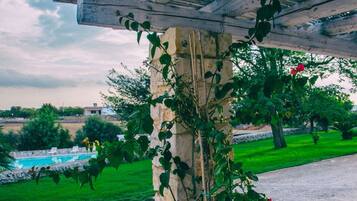 A stone pillar with climbing plants and a wooden pergola structure.