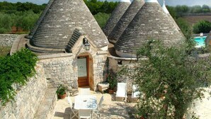 A stone building with conical roofs and a pool. - Masseria Cappuccini (Ostuni)