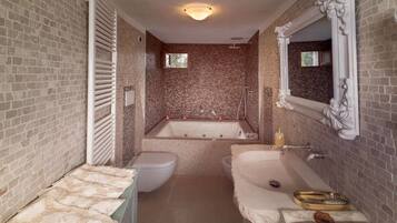 A bathroom with a bathtub, toilet, and sink, featuring a brick wall and a large mirror.