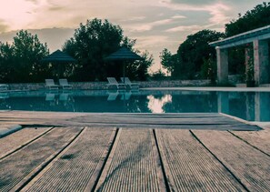 A wooden deck with lounge chairs and a swimming pool. - Masseria Cappuccini (Ostuni)