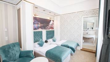 A hotel room with two beds, a large window with a cityscape view, a sitting area, and a bathroom with a mirror and sink.
