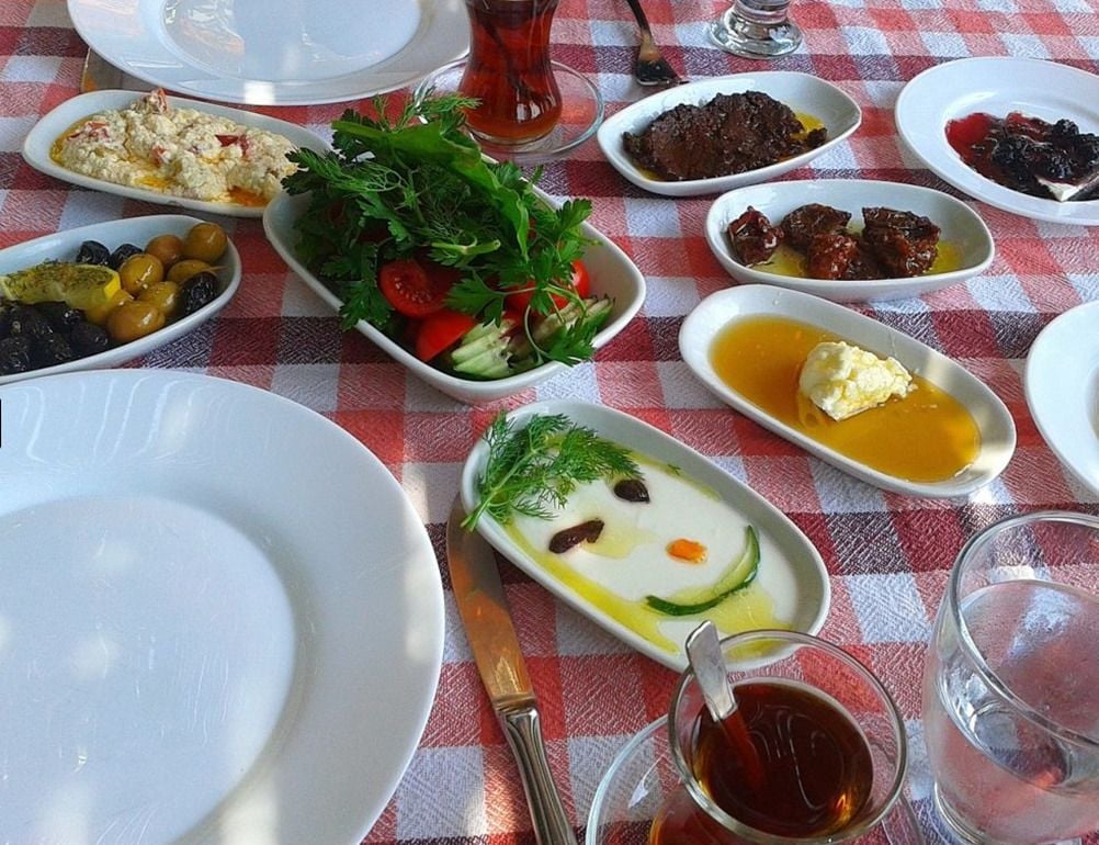 A table with various dishes and a glass of tea.