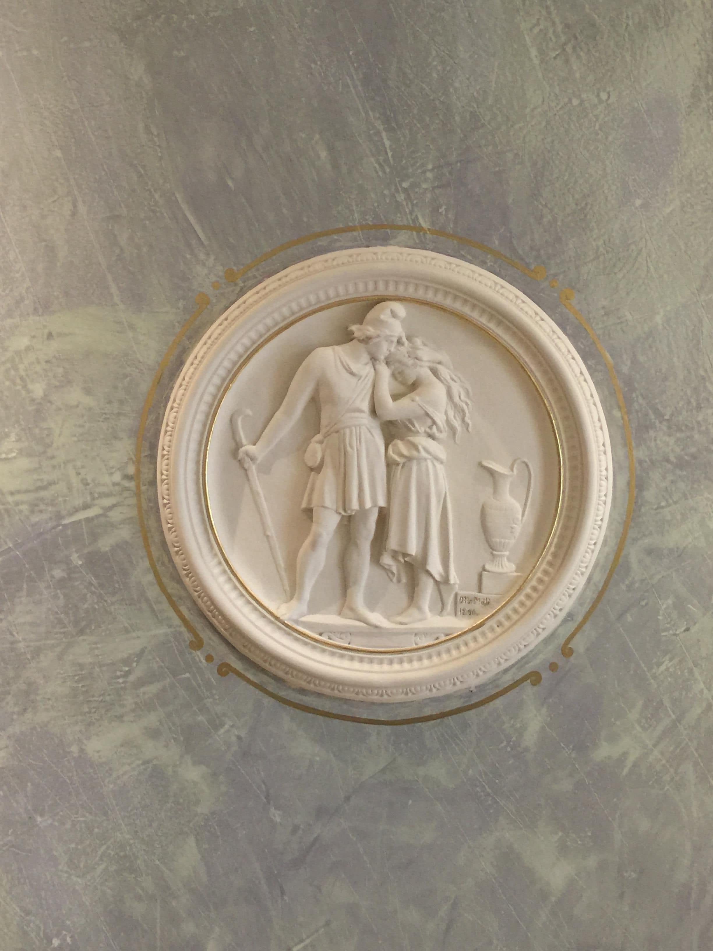 A white bas-relief sculpture on a textured wall.