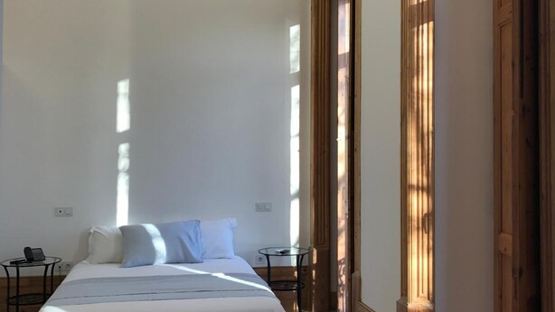 Een ruime kamer met een groot bed, een tafeltje en een stoel.