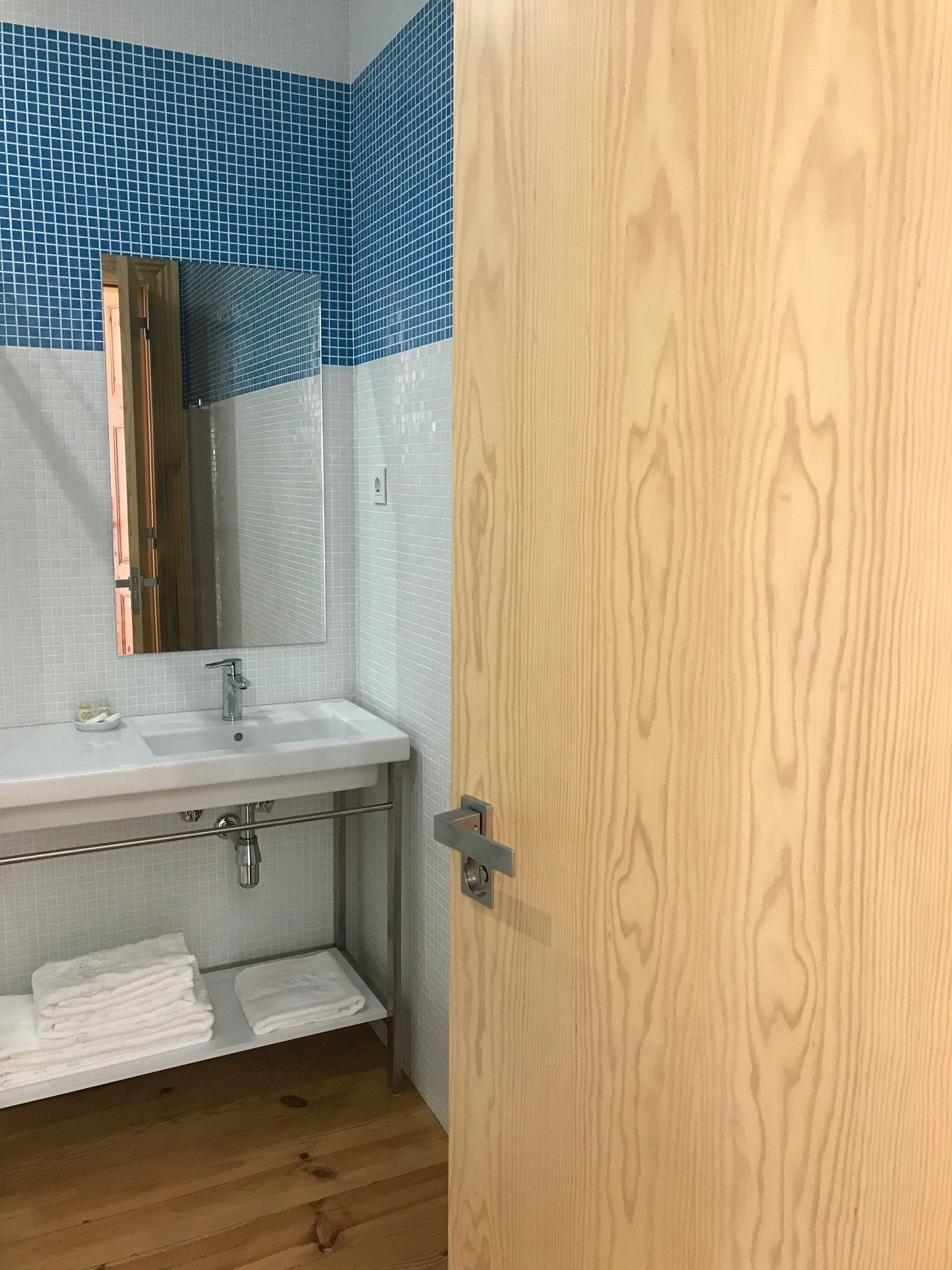 Un baño con lavamanos blanco, espejo y barra para toallas.