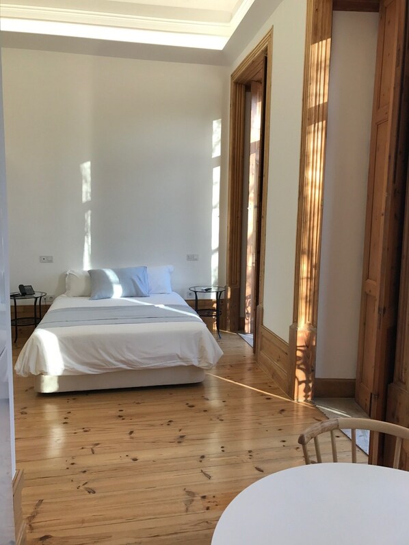 Una camera da letto con un letto grande, pavimento in legno e un tavolino.