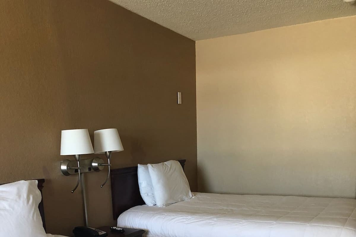 Ein Hotelzimmer mit zwei Betten, einem Nachttisch und einer Wandlampe.