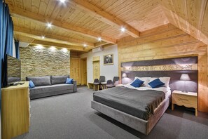 A bedroom with a large bed, a sofa, a desk, and a chair.
