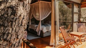A bedroom with a canopy bed, a glass door leading outside, and wooden furniture on a balcony.