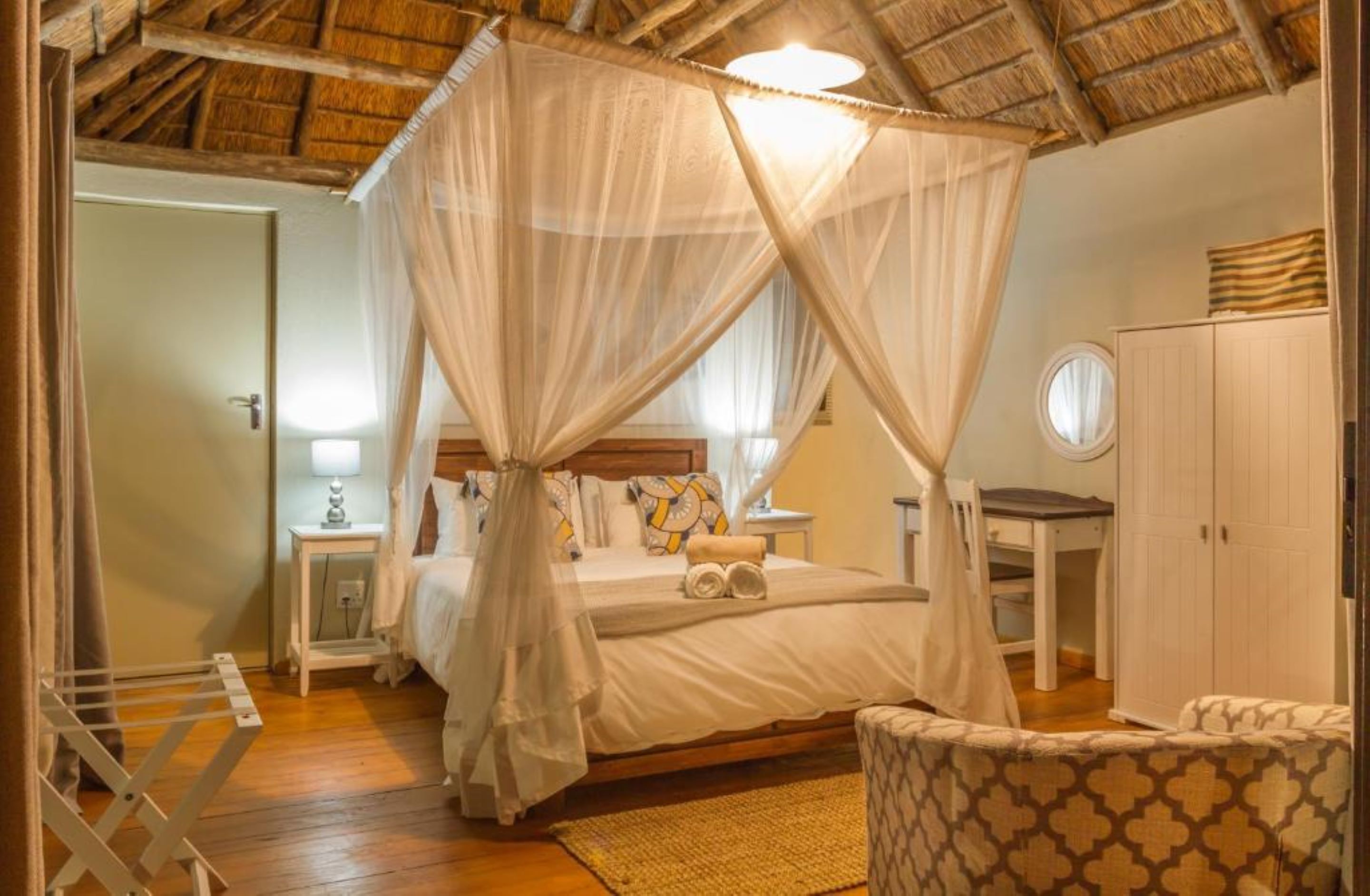A bedroom with a canopy bed, bedside tables, a wardrobe, and a chair.
