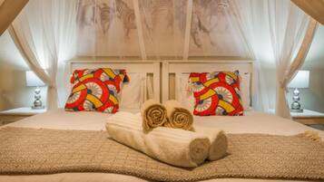Un dormitorio con cama con dosel, dos mesitas de noche y almohadones estampados.