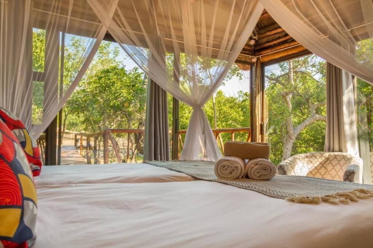 A room with a bed, a chair, and a view of trees.
