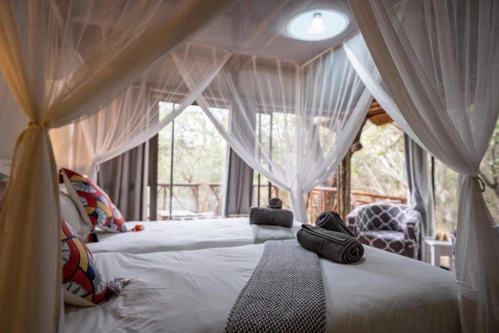 A room with two beds, a canopy, and a view of the outdoors.