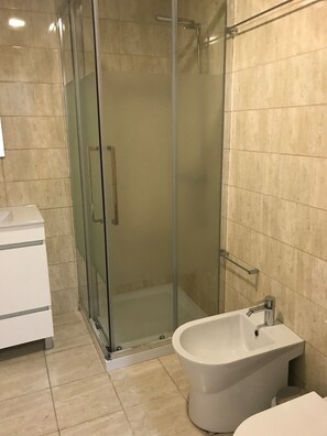 A bathroom with a glass-enclosed shower, a white sink, and a bidet. - Casa da Sé by PURUS (Coimbra)
