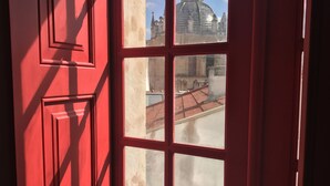 Una finestra con cornice rossa che si affaccia su un edificio con una cupola e guglie.