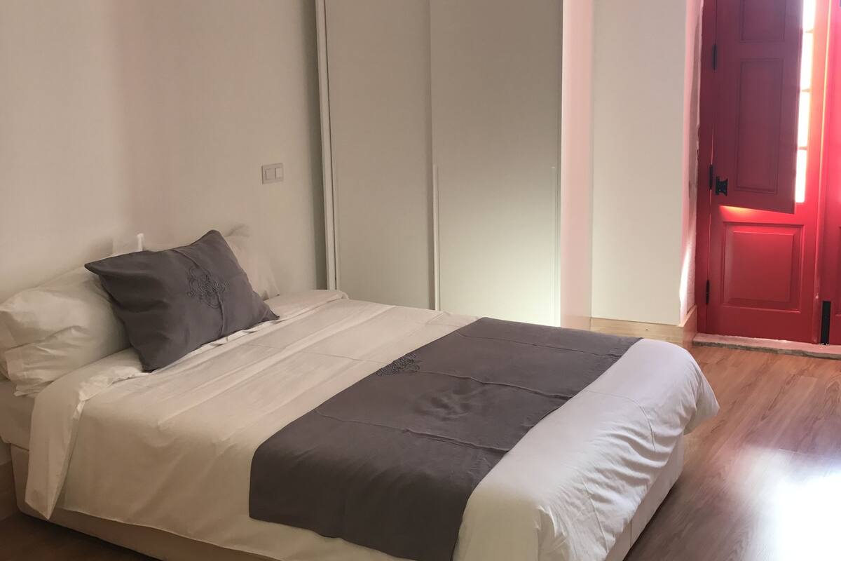 A bedroom with a bed, a wardrobe, and a red door.
