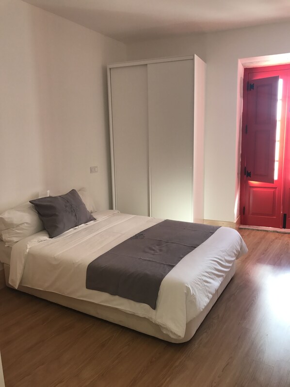 A bedroom with a bed, a wardrobe, and a red door. - Casa da Sé by PURUS (Coimbra)
