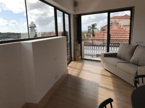 A spacious balcony with a view of a red-tiled roof building and palm trees. - Casa da Sé by PURUS (Coimbra)