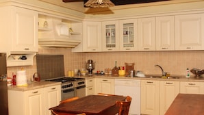 A kitchen with white cabinets, a wooden dining table, and various kitchen appliances. - Villa del Cardinale (Spoleto)