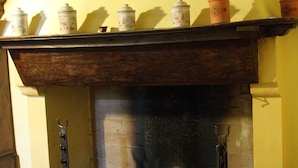 A fireplace with a brick base and a wooden mantel. - Villa del Cardinale (Spoleto)