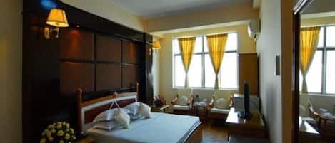 A hotel room with a large bed, bedside lamps, a desk, a chair, and a TV.