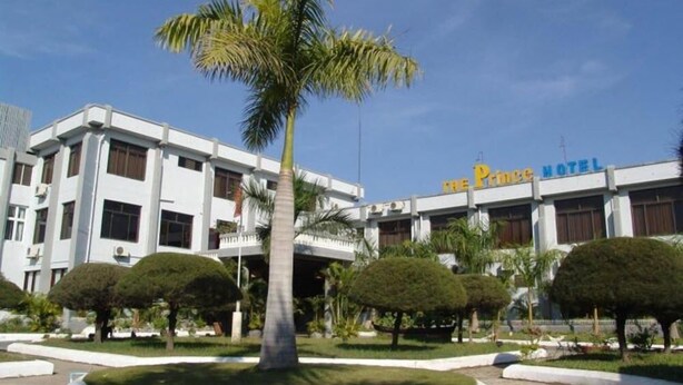 A hotel with a modern facade, palm trees, and a clear blue sky. - The Prince Hotel Mandalay (Mandalay)