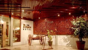 A hotel lobby with a wooden ceiling, a sign for 'The Prince Hotel', a vintage carriage, and potted plants. - The Prince Hotel Mandalay (Mandalay)