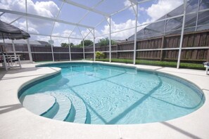 Una piscina con plataforma blanca y una zona cubierta con banco.
