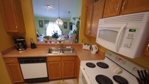 A compact kitchen with a dishwasher, stove, microwave, and double sink. - Ly53793 - Indian Ridge - 3 Bed 2 Baths Villa (Kissimmee)