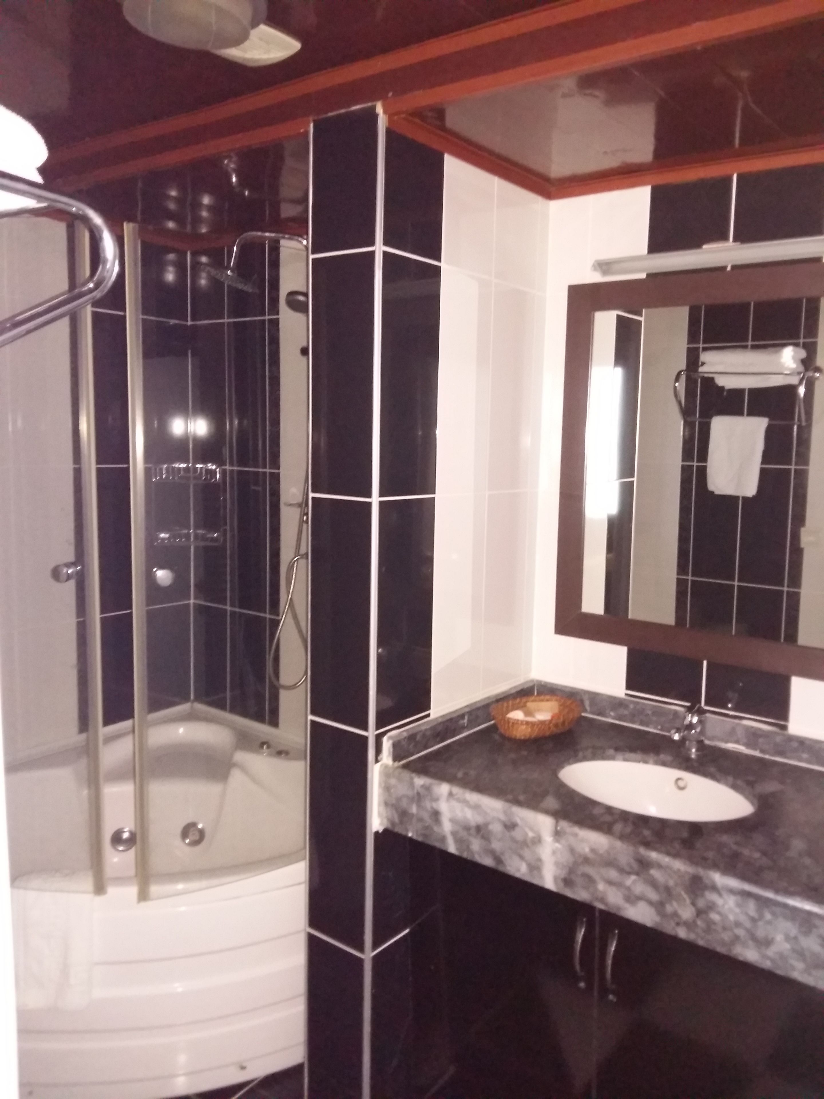 Un bany amb dutxa envidriada, una banyera blanca i un lavabo amb taulell de marbre.