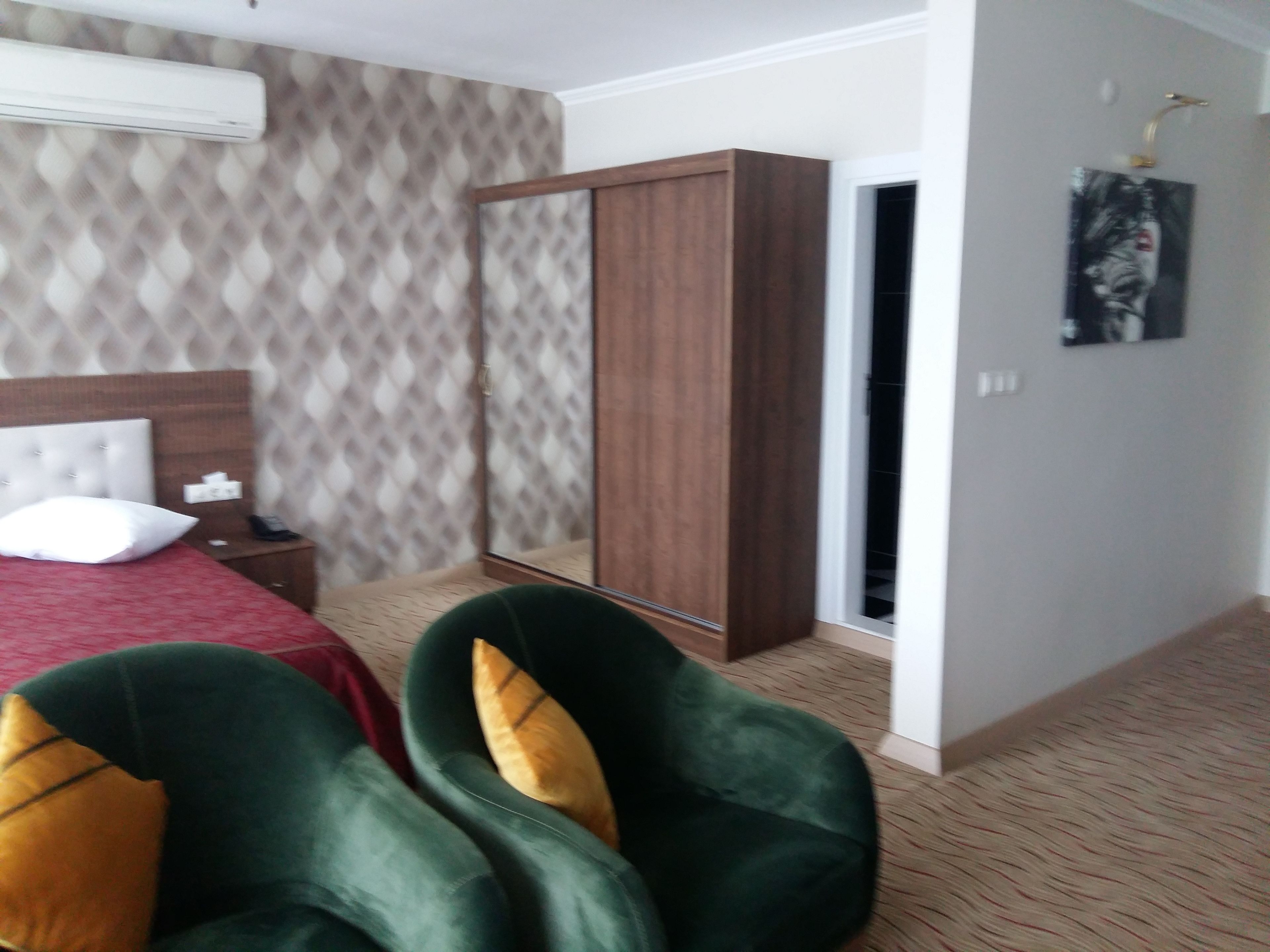 Una camera d'albergo con un letto, un armadio, un comodino e uno specchio.