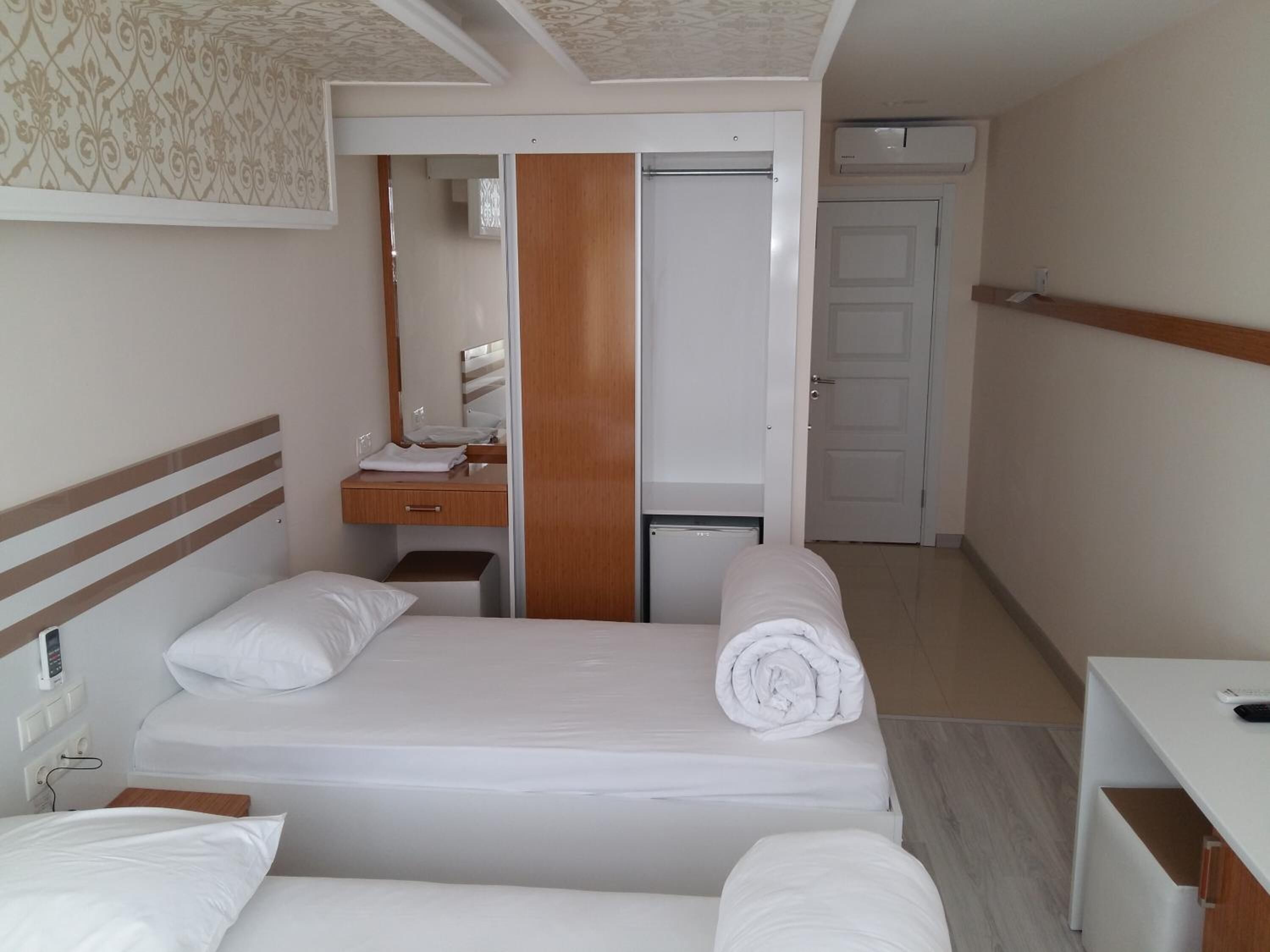 A hotel room with a bed, a desk, a mirror, and a wardrobe.