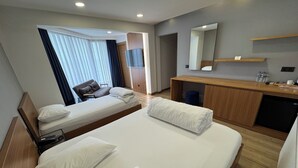 Een hotelkamer met een groot bed, een bureau, een stoel, een televisie en een spiegel.
