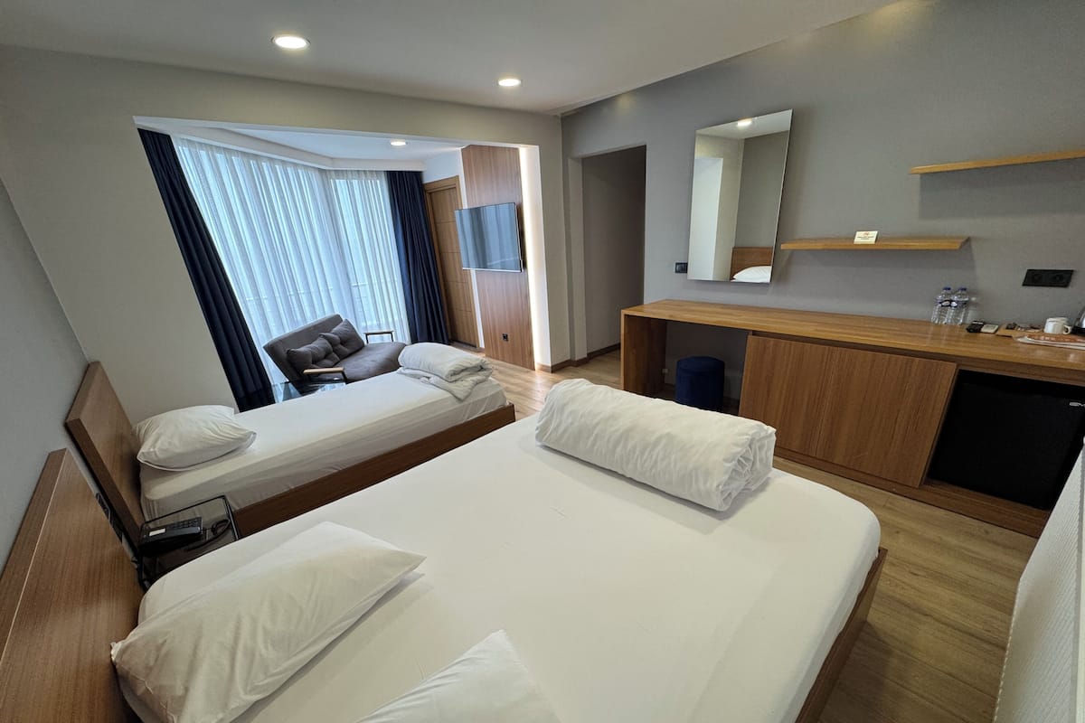 A hotel room with a large bed, a desk, a chair, a TV, and a mirror.