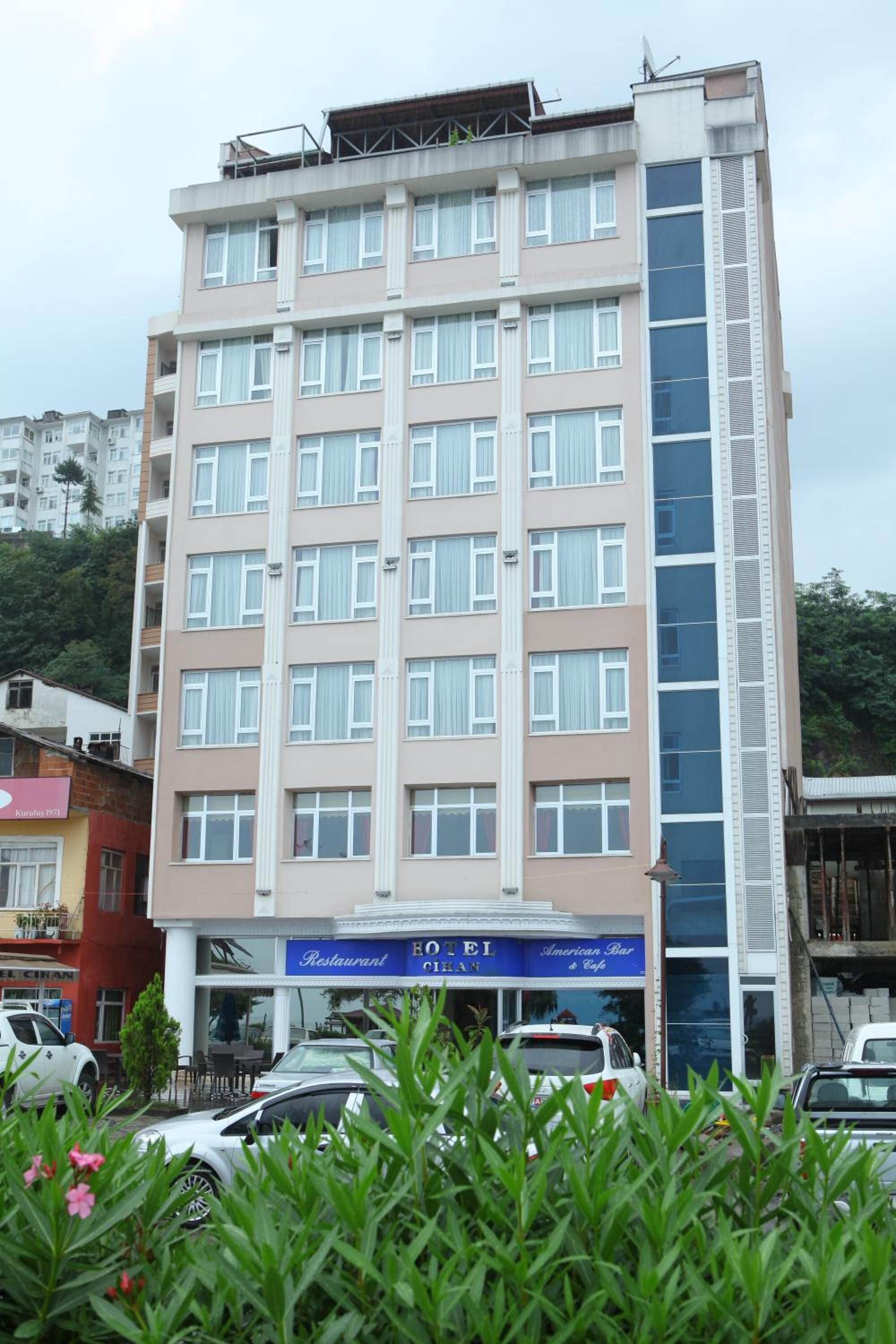 A multi-story hotel with a central entrance, balconies, and a restaurant on the ground floor.