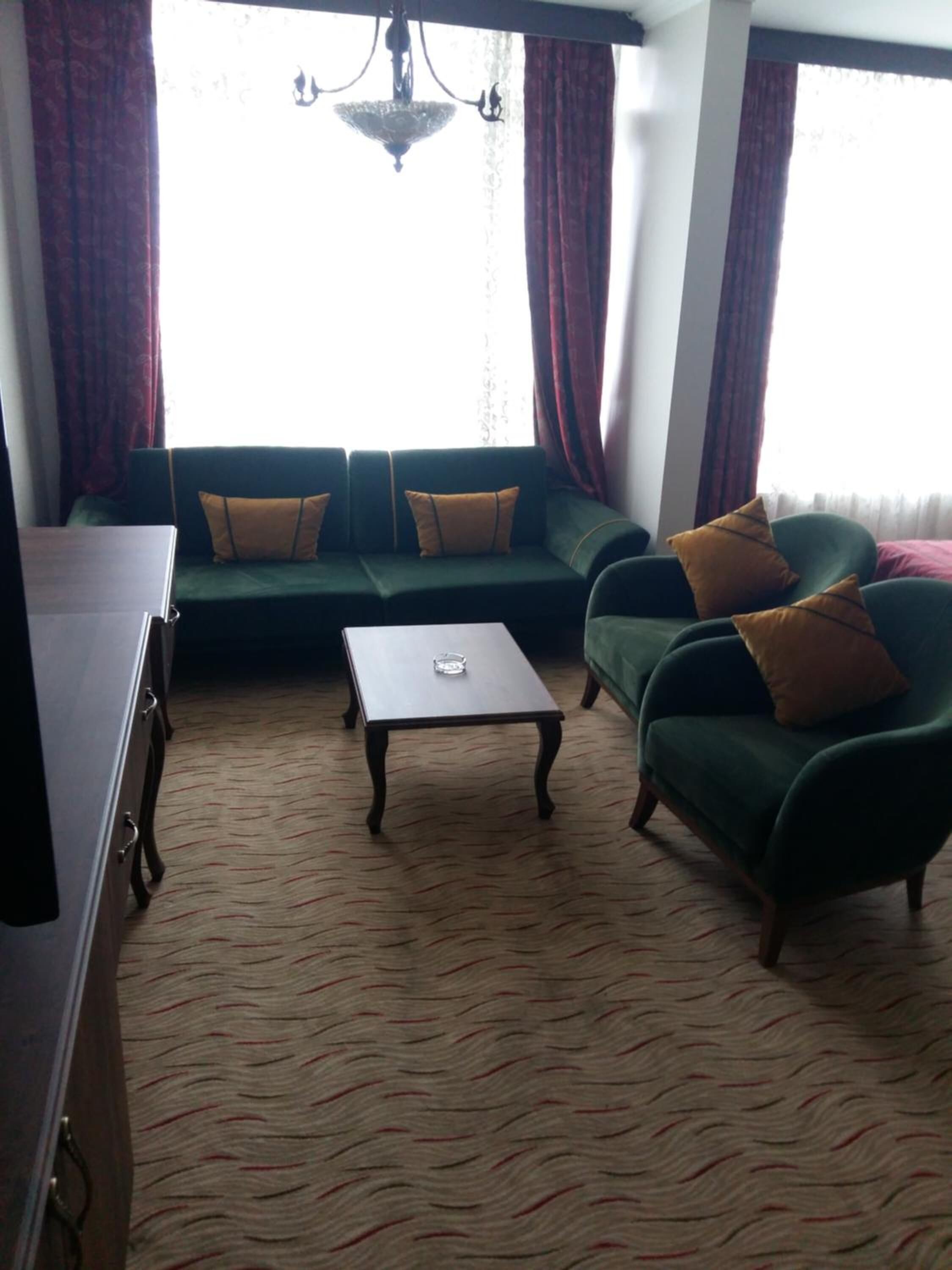 A living room with a green sofa set, a small table, and a cabinet.