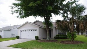 A single-story house with a garage, a driveway, and a well-maintained lawn. - Ly53798 - Indian Ridge - 4 Bed 2 Baths Villa (Kissimmee)
