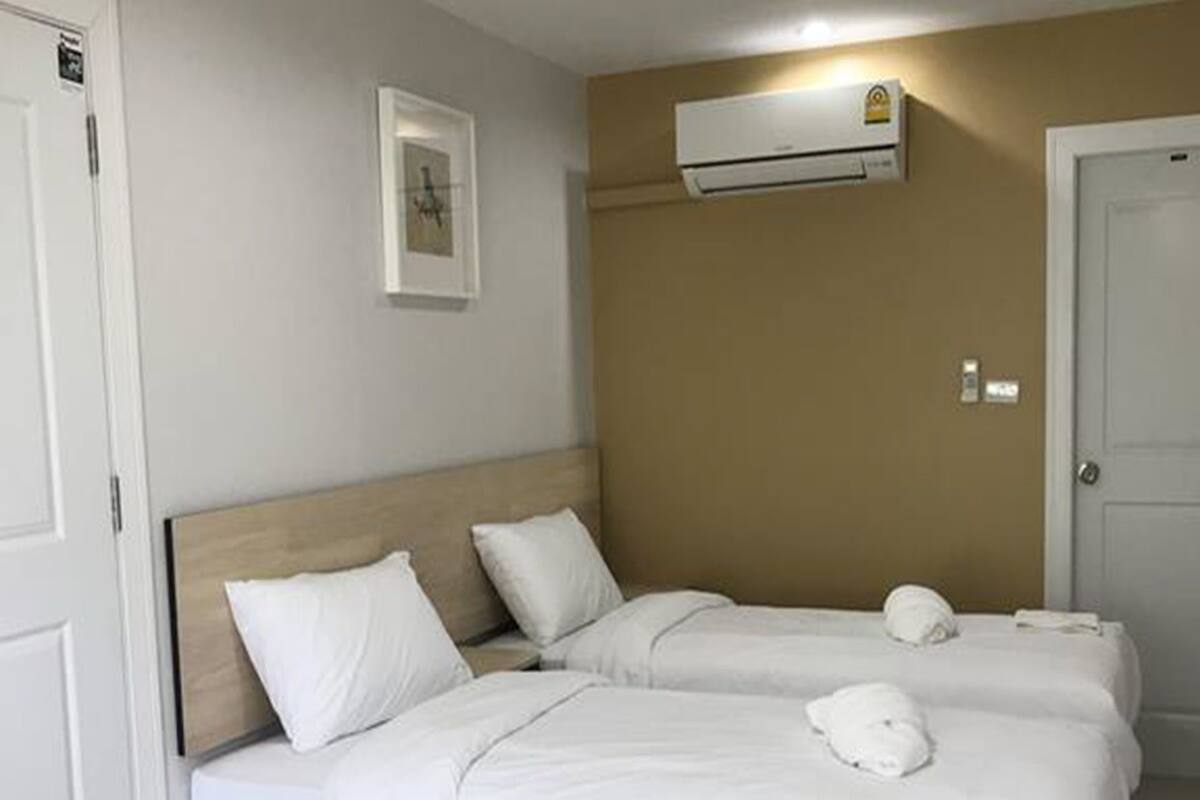 Una habitación de hotel con una cama doble, una mesita de noche y aire acondicionado instalado en la pared.