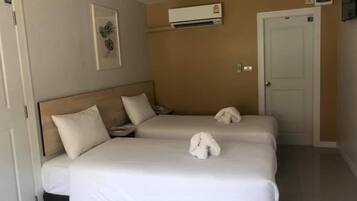 A hotel room with a double bed, a bedside table, a phone, an air conditioning unit, and a door.