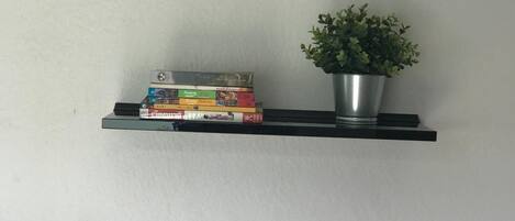 Una pared con tres estantes negros flotantes, cada uno con objetos diferentes.