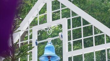 A white gazebo with a blue bell hanging from the center.