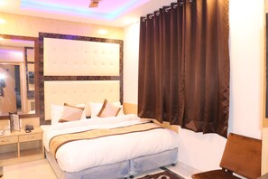 Una habitación de hotel con una cama grande, una mesita de noche, un espejo y una ventana con cortinas.