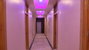 Ein Hotelgang mit Marmorboden, Holztüren und violetter Beleuchtung.