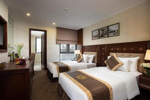 Habitación de hotel con dos camas, un escritorio y un comedor.