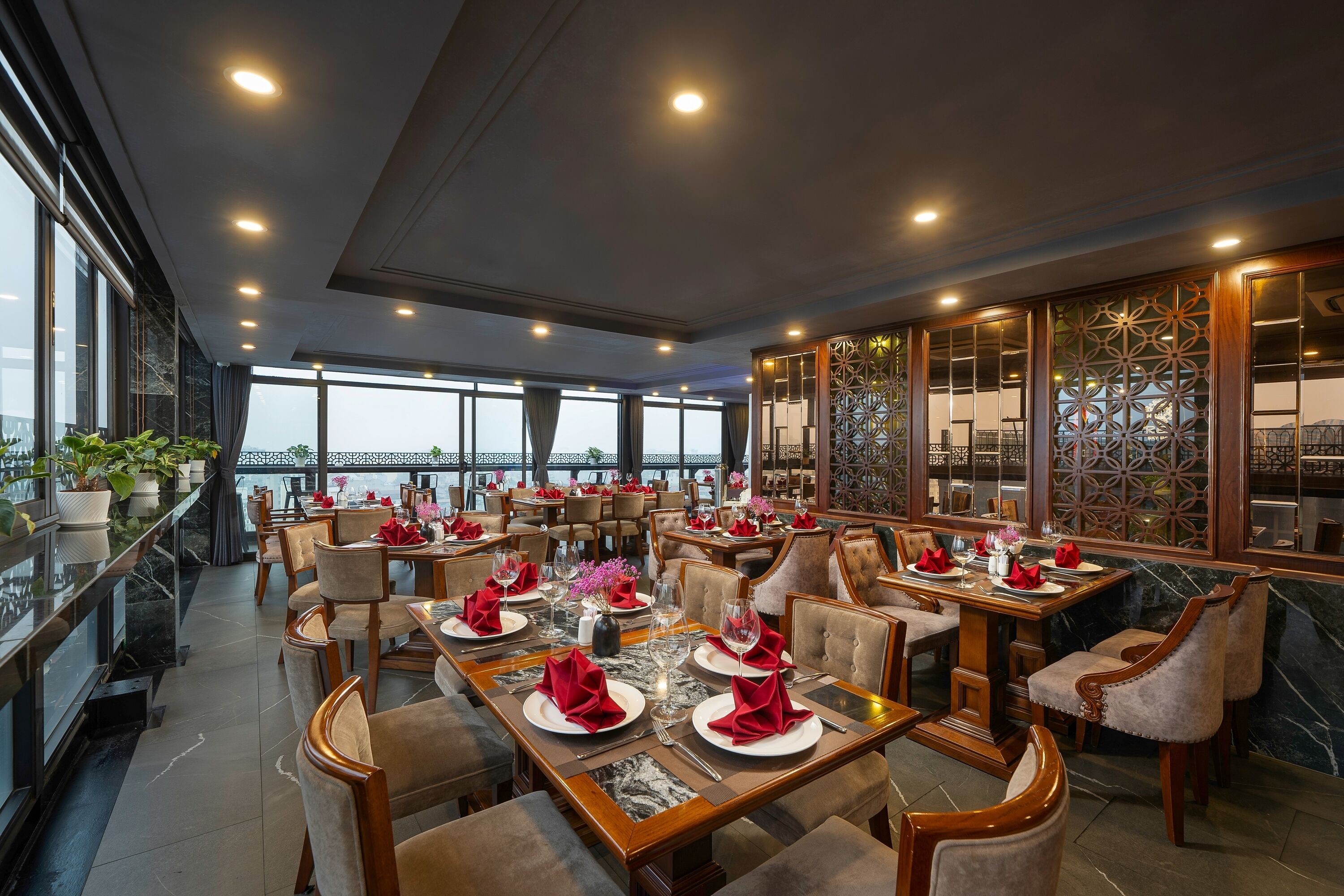 Ein Restaurant mit mehreren Tischen, großen Fenstern und Blick auf die Stadt.