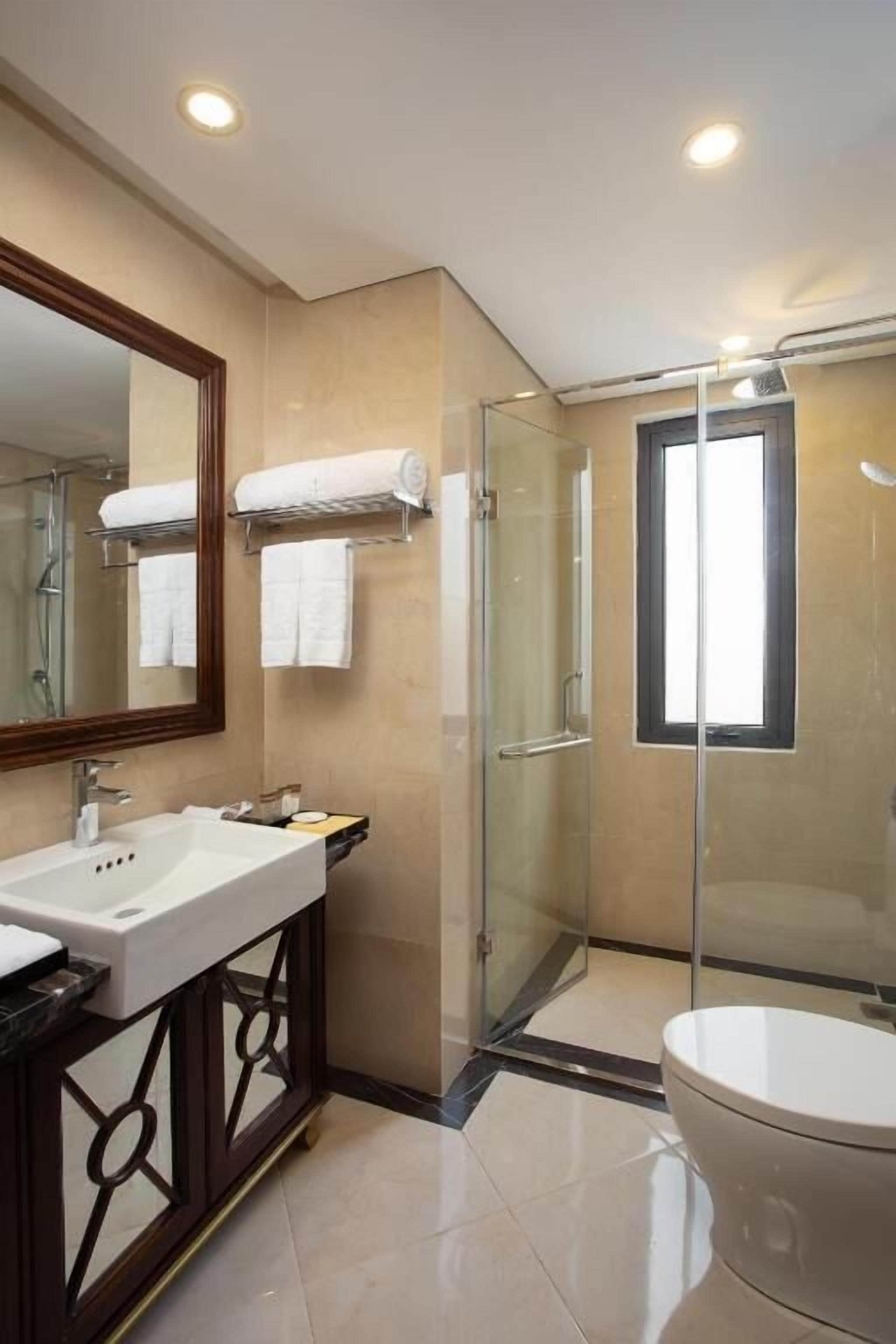 Een moderne badkamer met een douchecabine van glas, een grote spiegel en een toilet.