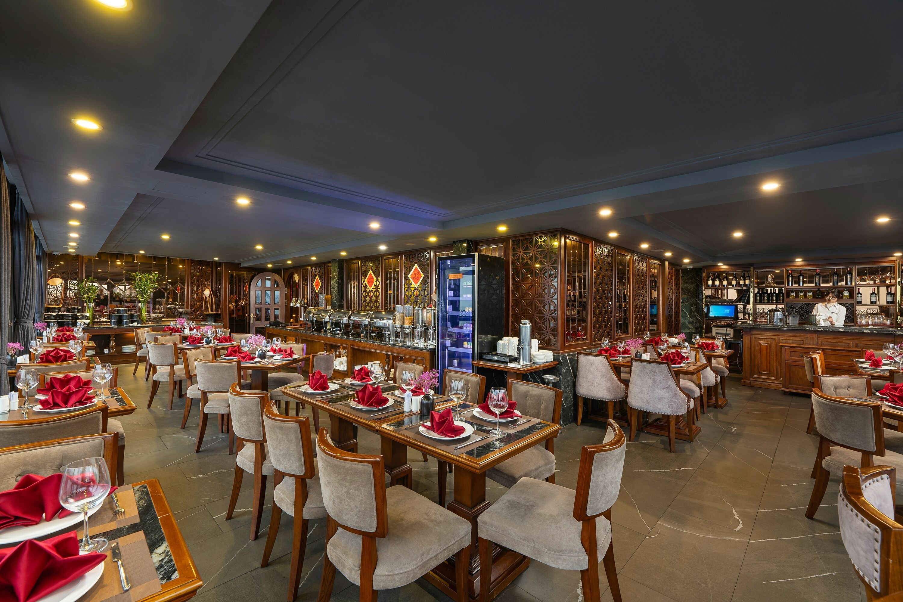 Un restaurante amplio con varias mesas dispuestas para comensales, una zona de bar con diversas bebidas y una decoración de estilo moderno.