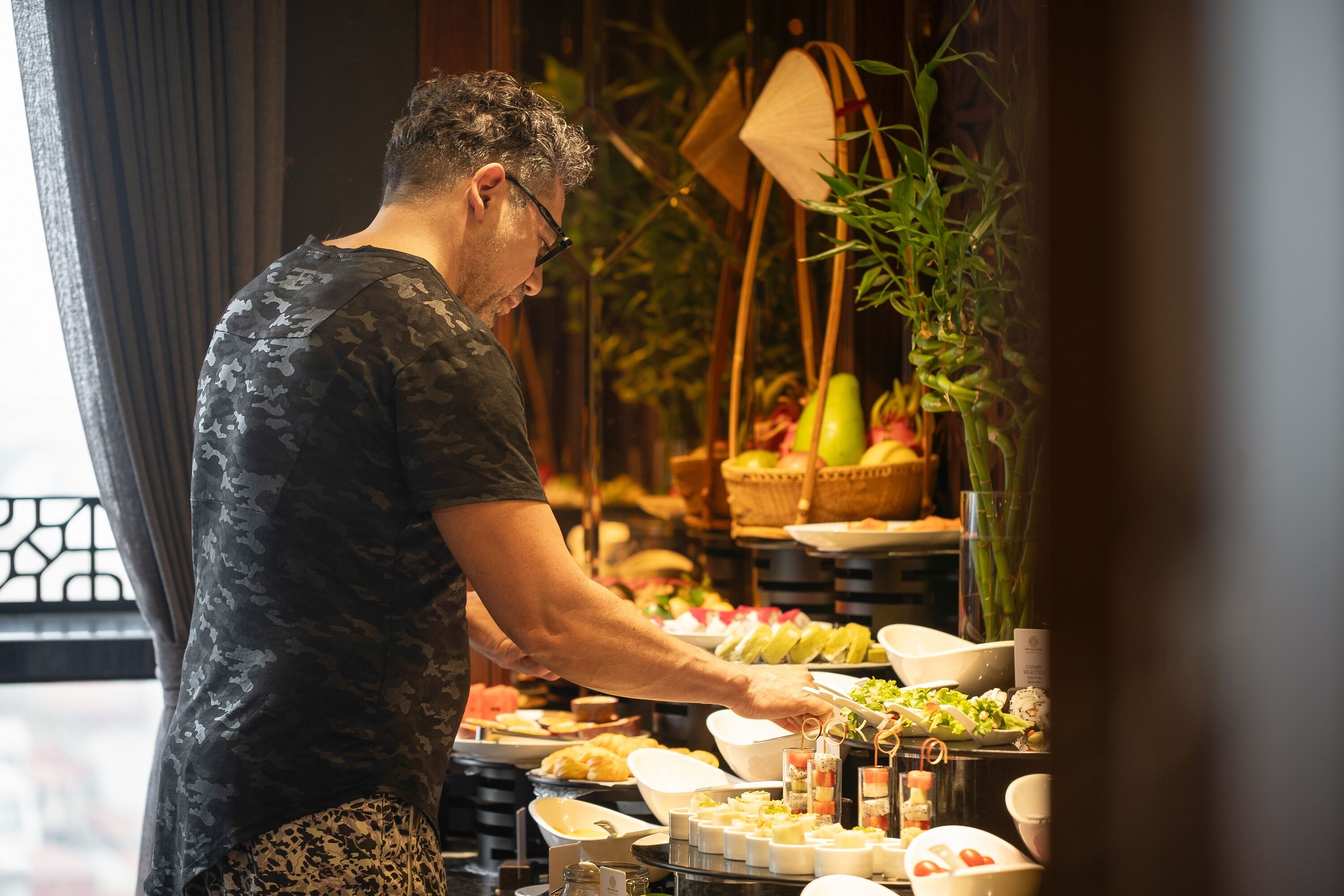A buffet setup with various food items and a person serving.