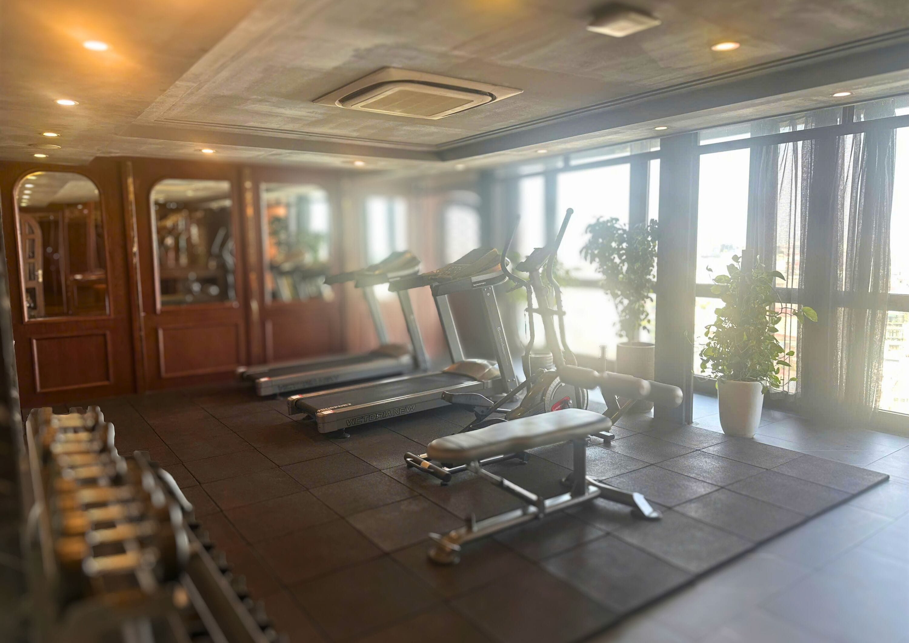 Un gimnasio con cintas de correr, elíptica y banco.